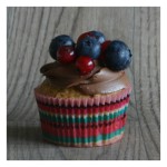Heller Victoria Sponge Cupcake mit einer dunklen Schokoladen Creme verziert mit Blaubeeren und Johannisbeeren.